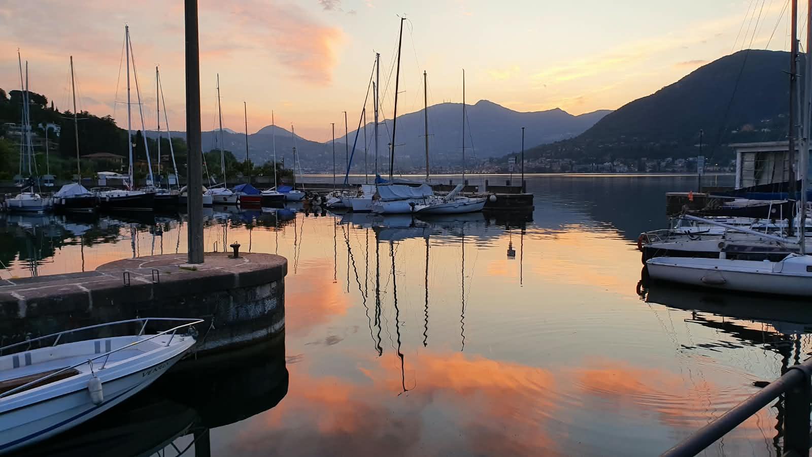 The harbour at dusk, sailing masts and the mountains behind.