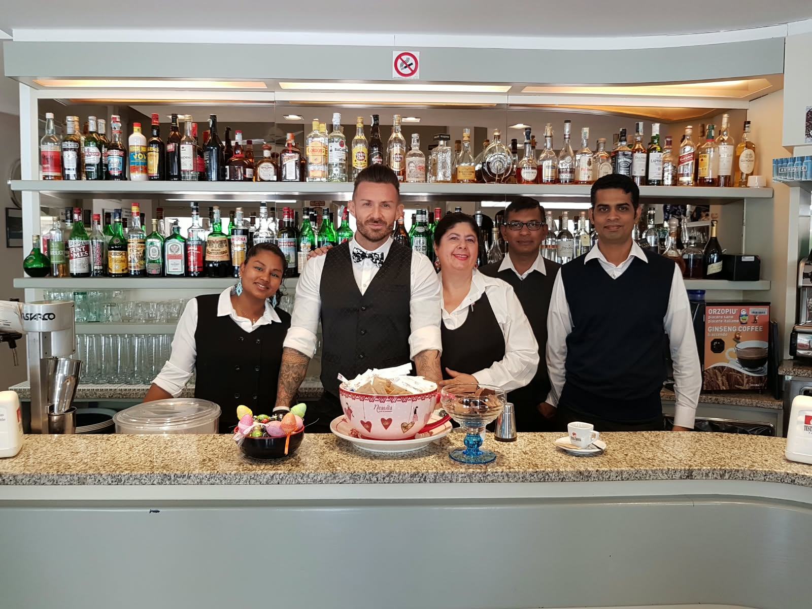The staff behind the bar counter, in front of the bottles.