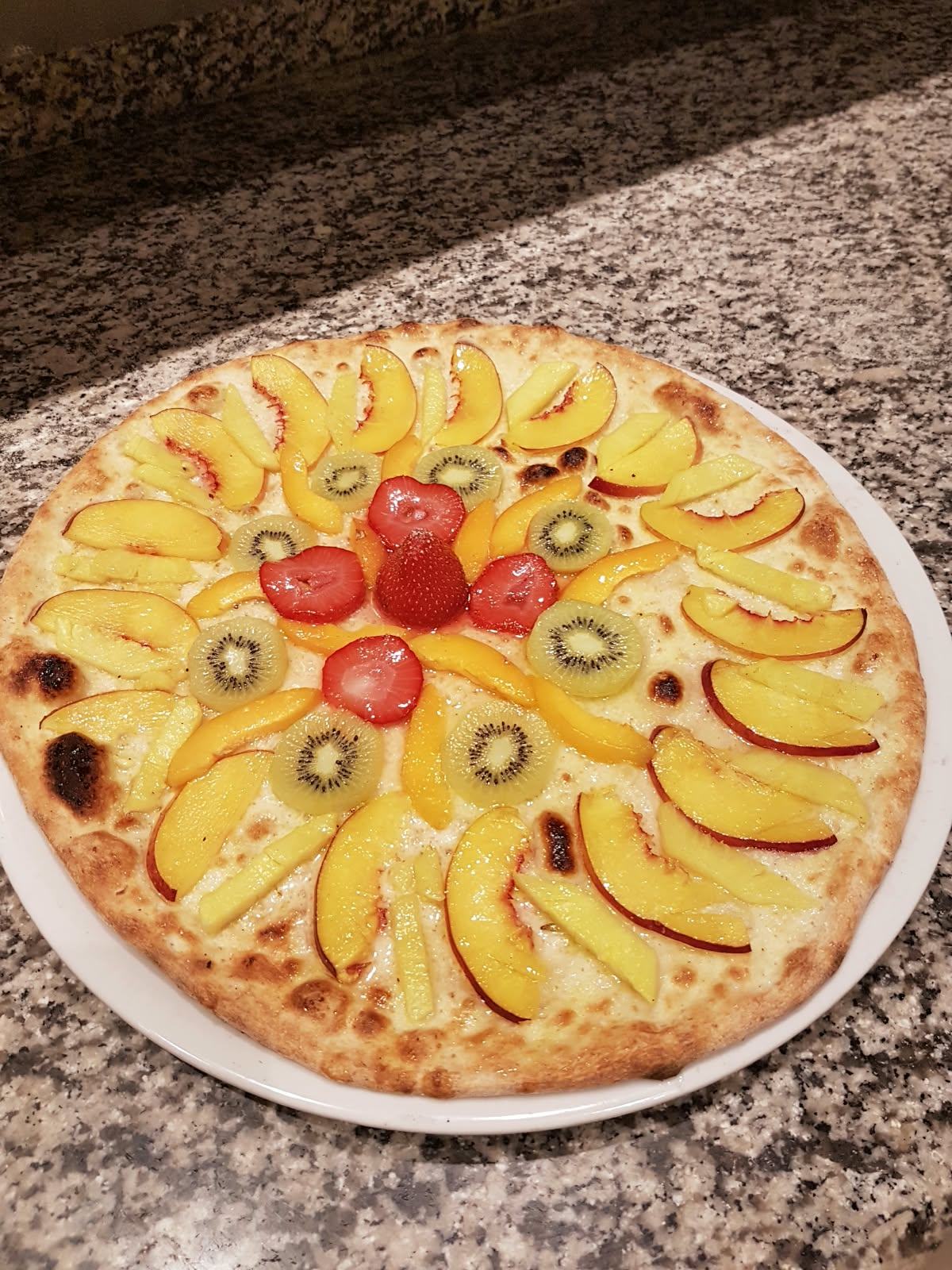 A sweet fruit pizza with peaches, kiwi and strawberries.