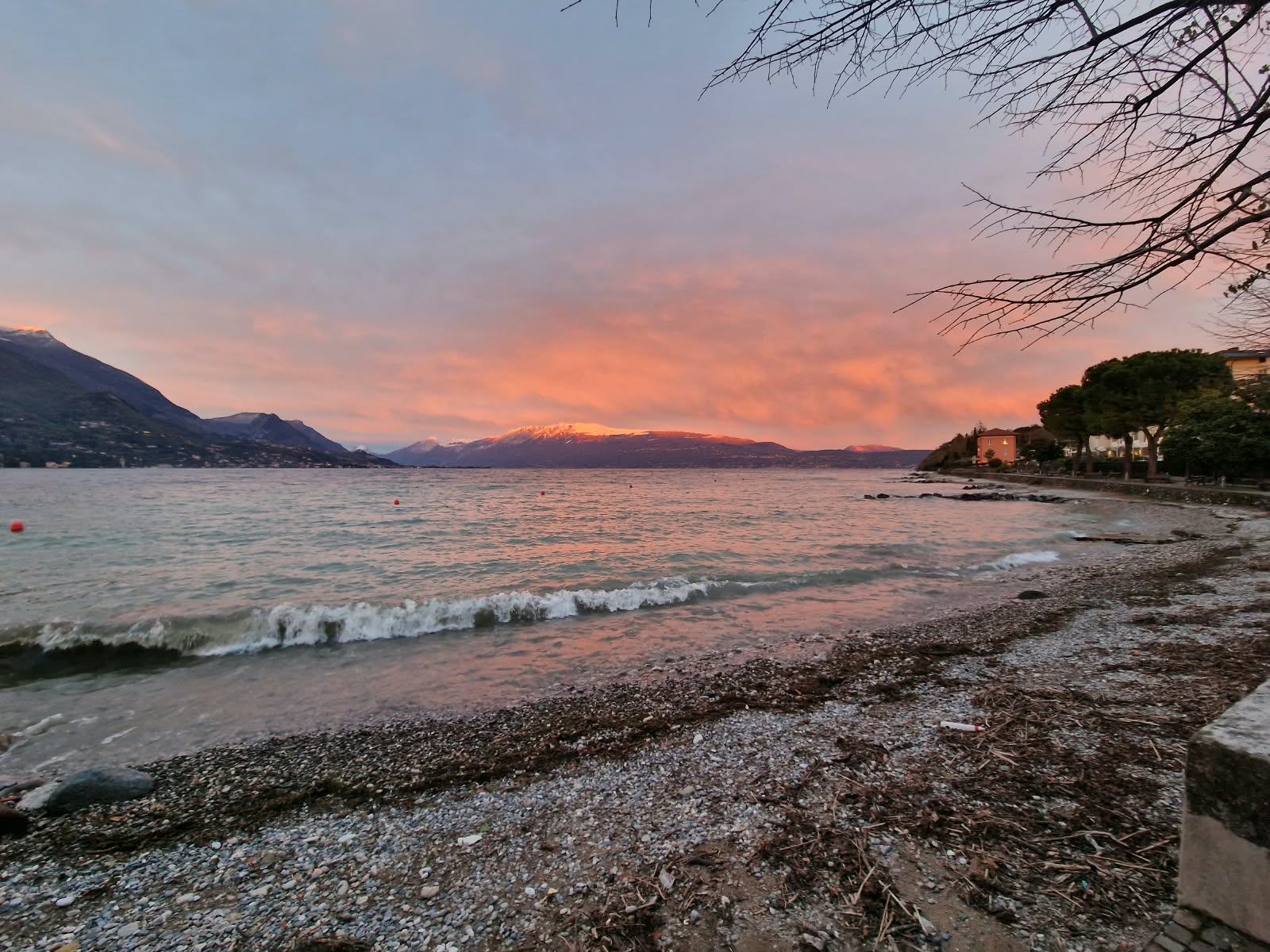 Sonnenuntergang über dem Kiesstrand, rosa Himmel über dem See.