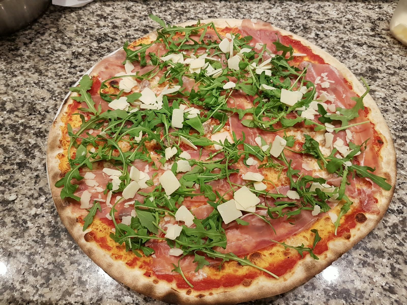 Eine Pizza mit Rohschinken, Rucola und Grana-Spänen.
