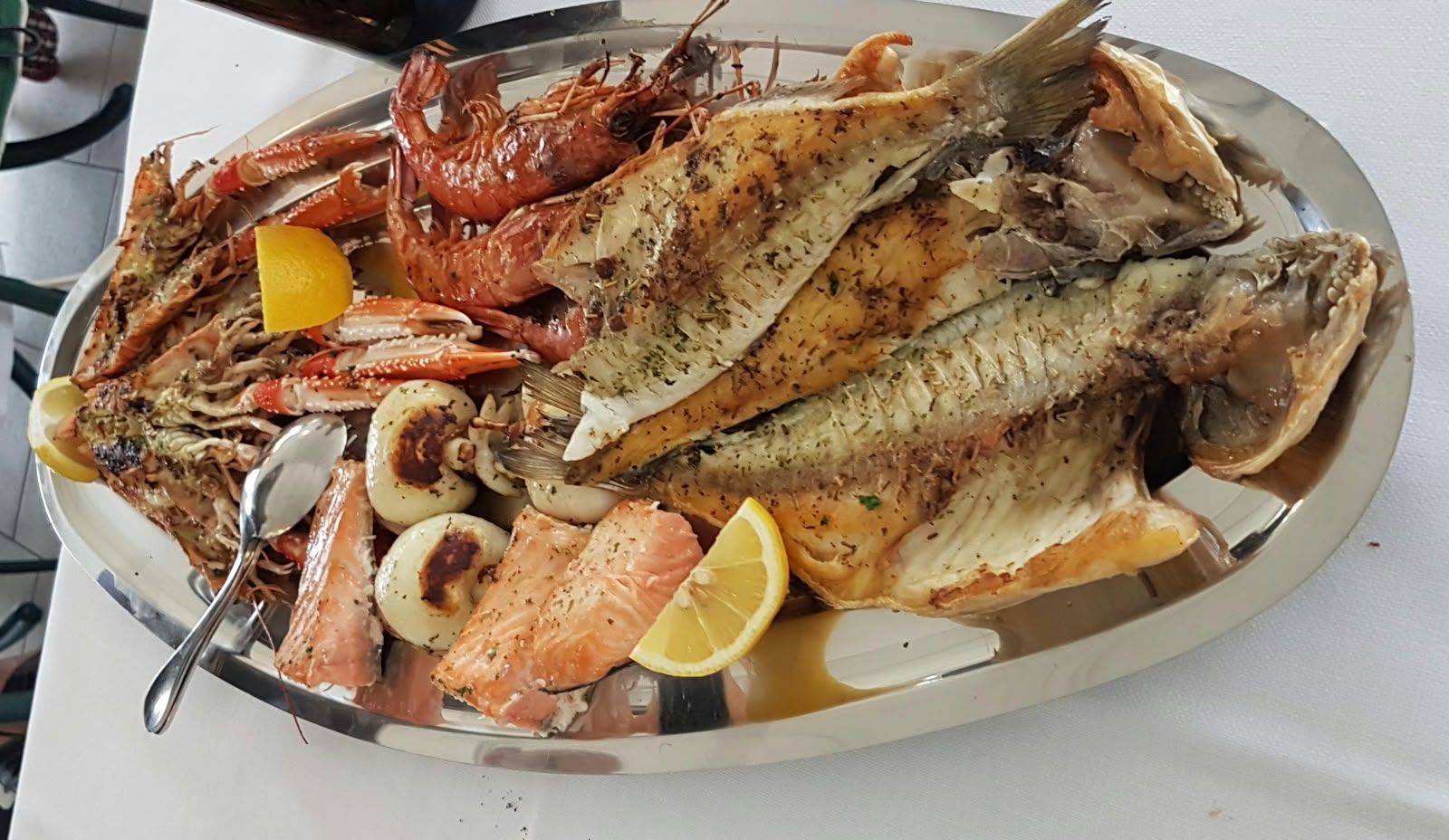 Eine gemischte Fischplatte: Garnelen, Filets und Zitrone.