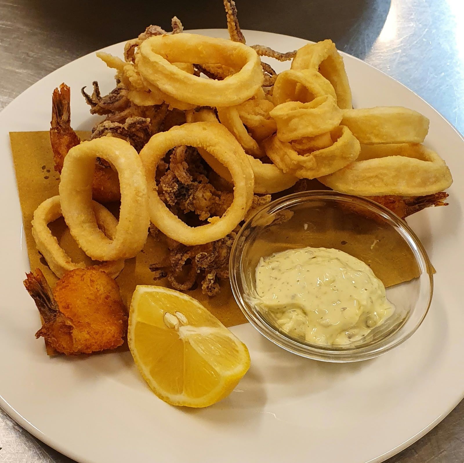 Frittierte Meeresfrüchte mit Calamari-Ringen, Garnelen, Pommes und Sauce.