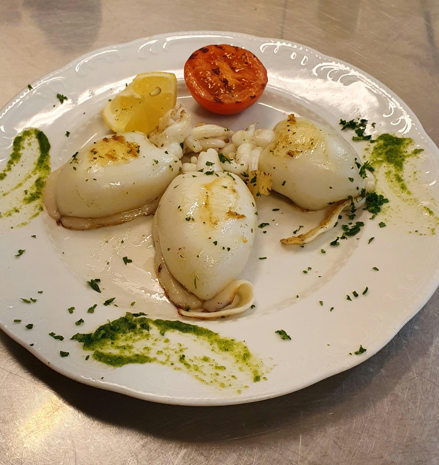 Tintenfisch mit gegrillter Tomate und Kräuteröl.