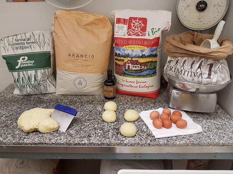 Auf der Arbeitsplatte: Mehlsäcke, die Waage, Teigkugeln, Eier und Mozzarella.