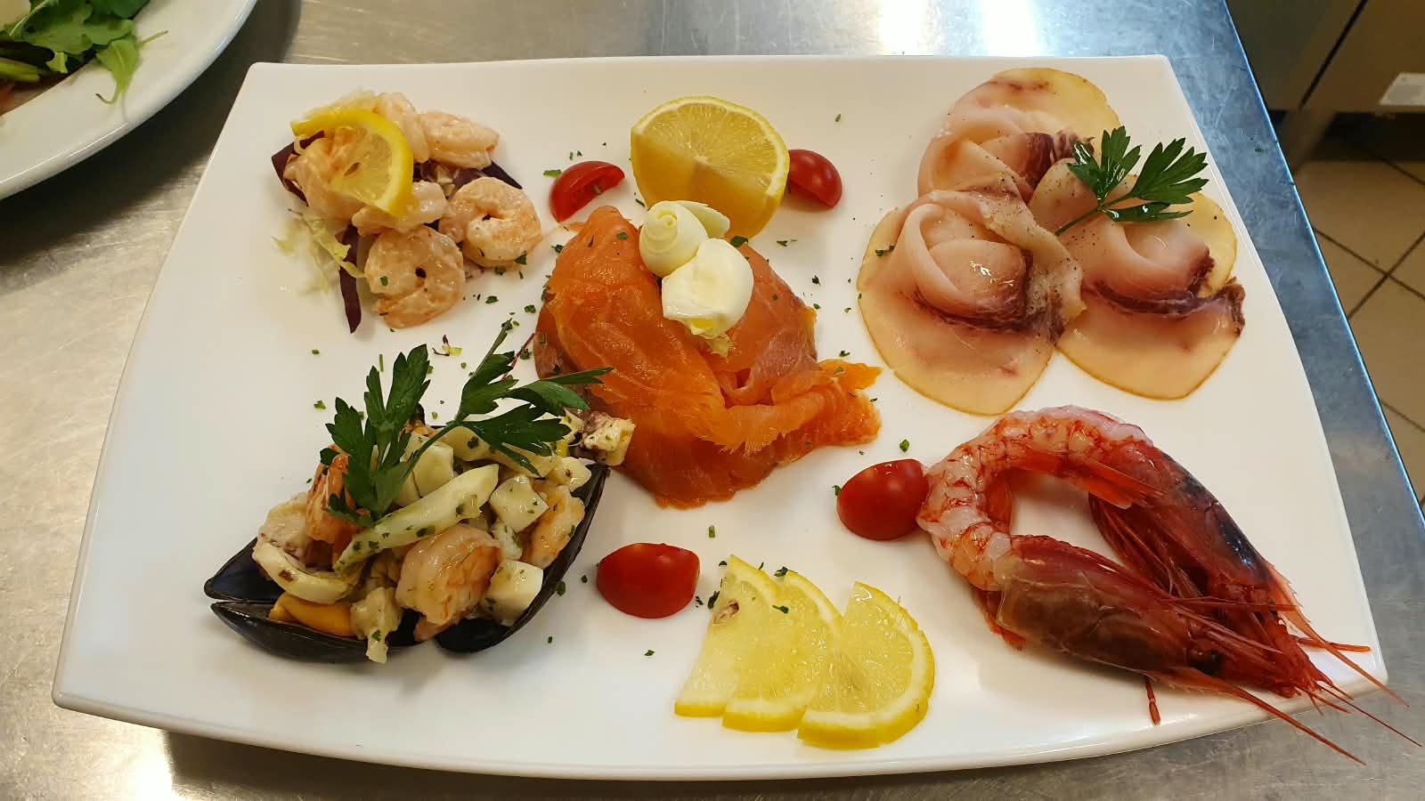 A plate of raw and smoked fish: prawns, salmon, carpaccio, mussels and lemon.