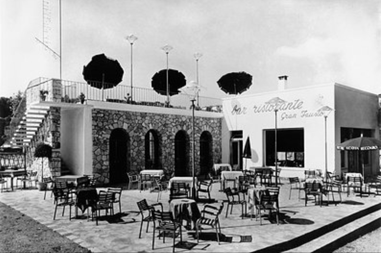 An old photograph of the place: tables under parasols and the painted sign reading “bar ristorante Gran Fausto”.